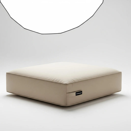 A single, square box-style seat cushion in a solid light beige color. The cushion is shown from a three-quarters angle and is isolated on a plain white background.