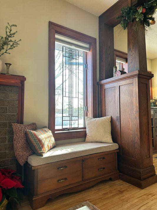 Craftsman-style window seat with custom light gray cushion over built-in storage drawers, prairie leaded glass window and dark oak woodwork