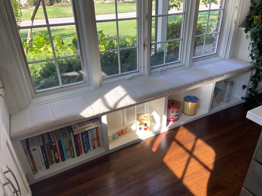 Custom beige window seat cushion made to exact measurements over a built-in storage bench