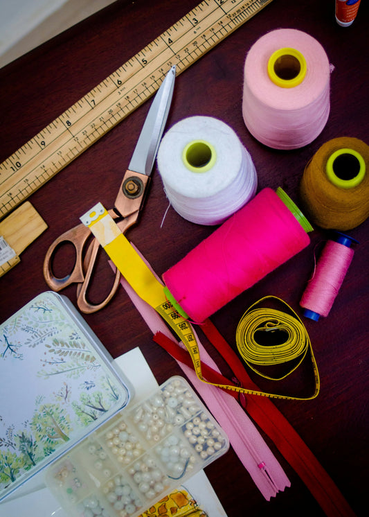 DIY window seat cushion sewing supplies laid out — ruler, fabric scissors, thread, zipper and measuring tape