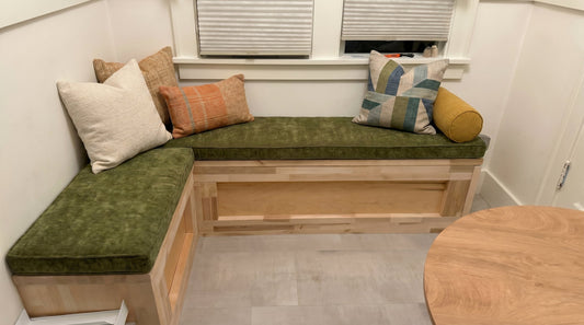 Custom L-shaped kitchen nook bench cushion in olive green, installed in a wood-toned breakfast nook