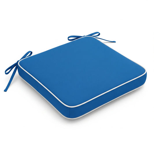 Isolated square seat cushion in bright royal blue with white piping and four dark blue ties extending from the corners. It casts a slight shadow on a plain white background.