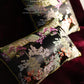 Close-up of gold metallic embroidery showing flowering trees and pavilion details on burgundy velvet cushion