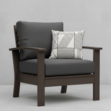 Deep seating replacement cushions in dark colors on outdoor furniture surrounded by greenery.