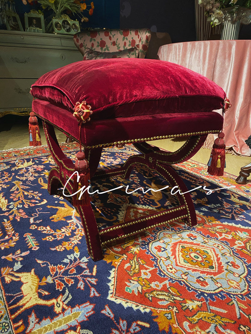 Geometric Persian rug pattern detail in burgundy, blue, orange and gold on velvet ottoman