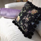 Hand-stitched rose embroidery detail on black chenille pillow with gold and purple floral pattern